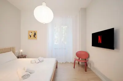 a white bedroom with a bed and a chair at Pop Domus Guest House o Affittacamere in Rome