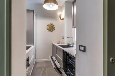 a white kitchen with a sink and a dishwasher at Trevi Central Suite in Rome