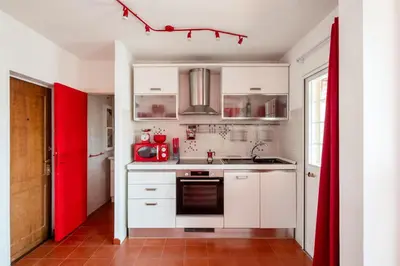 a kitchen with white cabinets and a red door at Vatican PENTHOUSE in Rome