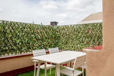 a white table and chairs next to a wall with roses at Vatican PENTHOUSE in Rome
