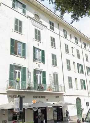 a large white building with green shuttered windows at La Casabella Rome Center in Rome