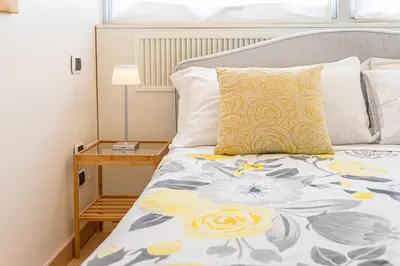 a bed with a yellow pillow and a side table at Appartamento Vacanze a Roma San Giovanni - Affitto Breve, Comfort Moderno e Posizione Centrale in Rome