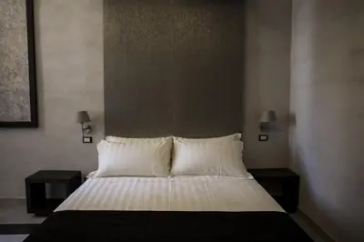 a bed with white sheets and pillows in a room at Campo De’ Fiori Prestige Rooms in Rome