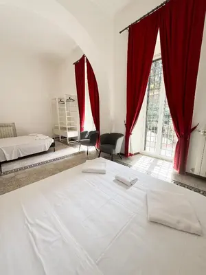 a bedroom with a large white bed with red curtains at Sant'Onofrio Boutique Apartment in Rome