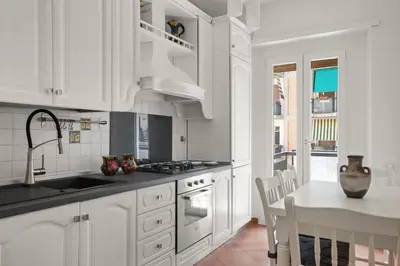 a kitchen with white cabinets and a sink and a table at Betti Classic Home in Rome