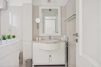 a white bathroom with a sink and a mirror at Betti Classic Home in Rome