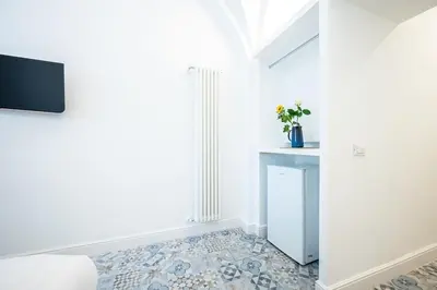 a white room with a television and a floor at Aeterna RHome - Domus Piramide in Rome