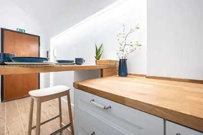 a kitchen with white cabinets and a counter with a stool at Aeterna RHome - Domus Piramide in Rome