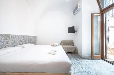 a white bedroom with a large bed and a couch at Aeterna RHome - Domus Piramide in Rome