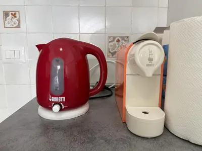 a red tea kettle on a counter next to a scale at Metro A Battistini - Ramat House in Rome