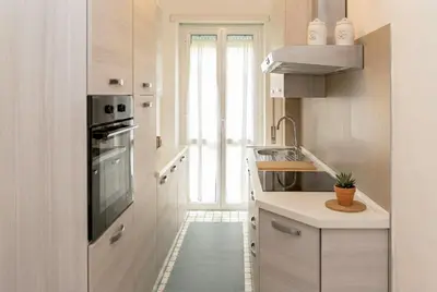 a white kitchen with a sink and a stove at Urban Nest - Trastevere by RHR in Rome