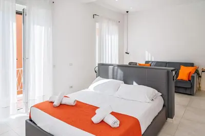 a bedroom with a bed with white sheets and orange blanket at Ottavilla Apartment in Rome