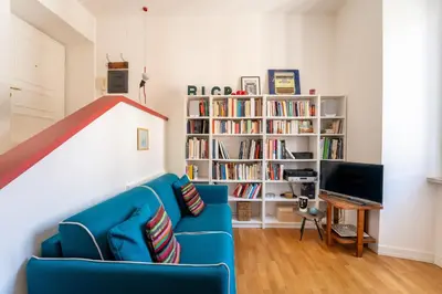 a living room with a blue couch and a book shelf at Casa Medina, Charme in 5 min From Villa Borghese in Rome