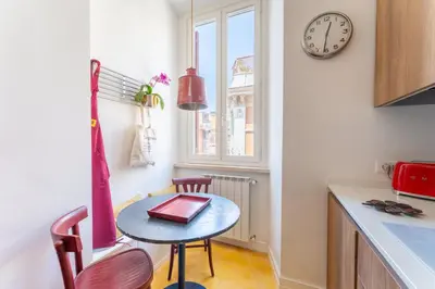 a kitchen with a small table and a clock on the wall at Casa Medina, Charme in 5 min From Villa Borghese in Rome