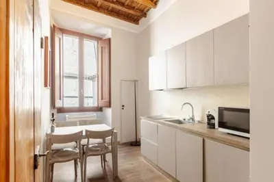 a kitchen with white cabinets and a table and chairs at Stunning 2bedrooms apartment with AC Via Giulia in Rome