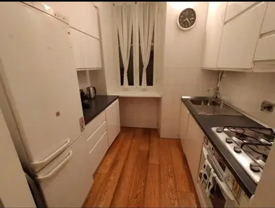 a kitchen with a white refrigerator and a wooden floor at Suite Tevere star in Rome