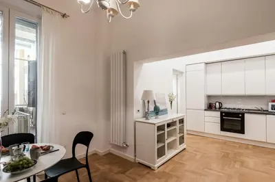 a white kitchen and dining room with a table and chairs at The Best Rent - Modern one-bedroom apartment in the Porta Pia area in Rome