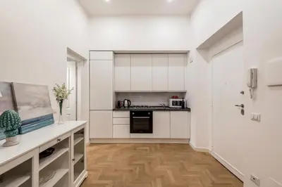 a kitchen with white cabinets and a wooden floor at The Best Rent - Modern one-bedroom apartment in the Porta Pia area in Rome