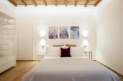 a white bedroom with a large bed and three paintings on the wall at Margherita Flat in Rome