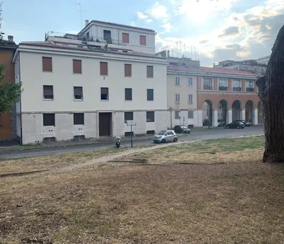 a large white building with cars parked in a parking lot at Aventino The Yellow Home in Rome
