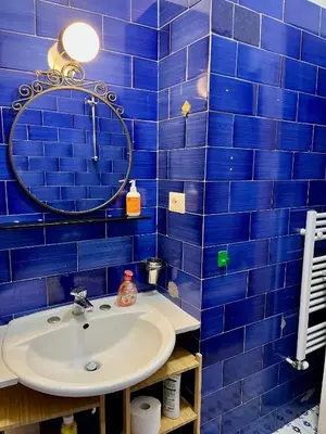 a blue tiled bathroom with a sink and a mirror at Trastevere Hideaway in Rome