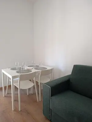 a white table with wine glasses on it next to a green couch at Rome Tiburtina Terrace Inn - casa vacanze in Rome
