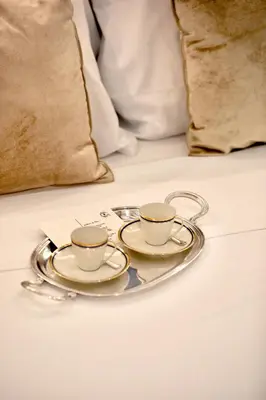 two coffee cups on a plate on a bed at Boutique Apartment Steps from Colosseum in Rome
