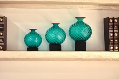 three green glass vases sitting on a shelf at Boutique Apartment Steps from Colosseum in Rome