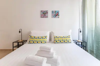 a bedroom with a white bed with towels on it at Hostly Forlanini Family Apartment near Gianicolo in Rome