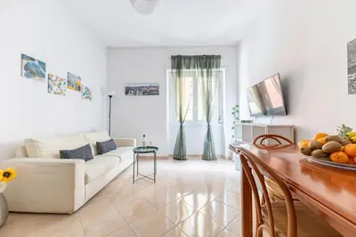 a living room with a white couch and a table at Hostly Forlanini Family Apartment near Gianicolo in Rome