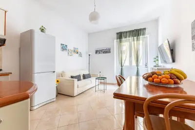 a kitchen and living room with a table with a bowl of fruit at Hostly Forlanini Family Apartment near Gianicolo in Rome