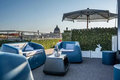 a patio with blue chairs and an umbrella and a table at Gracchi Vatican View in Rome