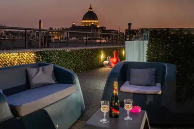 a patio with two chairs and two glasses of wine at Gracchi Vatican View in Rome