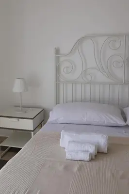 a white bedroom with a white bed and a nightstand at Dimora Trasteverina Holiday Home in Rome