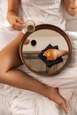 a woman sitting on a bed with a mirror with a meal at Efes Hôtellerie in Rome