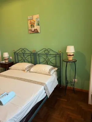a green bedroom with a bed and two lamps at DolceCasa - Re di Roma Apartment in Rome