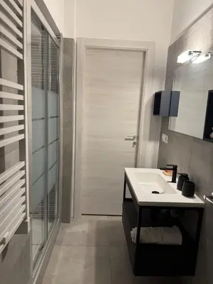 a bathroom with a white sink and a door at DolceCasa - Re di Roma Apartment in Rome