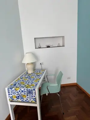 a white desk with a lamp and a chair at DolceCasa - Re di Roma Apartment in Rome