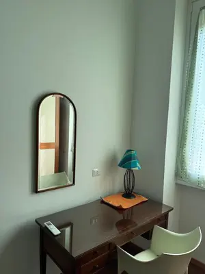 a desk with a mirror and a chair and a lamp at DolceCasa - Re di Roma Apartment in Rome