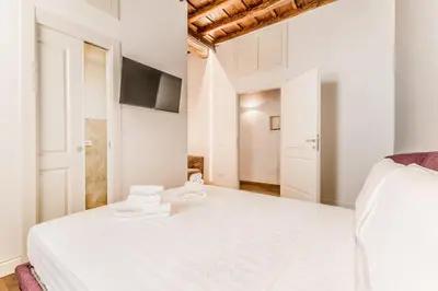 a white bedroom with a bed and a tv at APT ROME Fratte di Trastevere in Rome