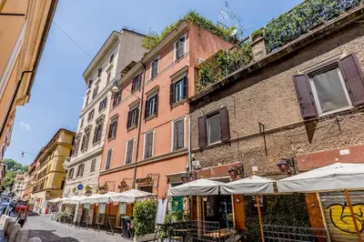 a building with tables and umbrellas on a city street at APT ROME Fratte di Trastevere in Rome