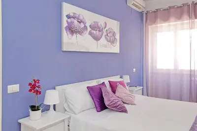 a bedroom with purple walls and a white bed with purple pillows at Victoria Apartment in Rome