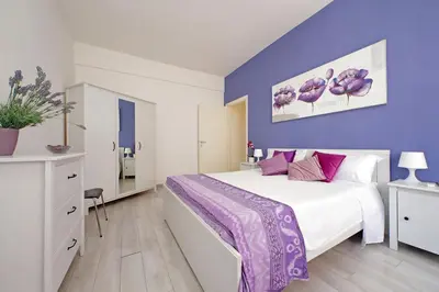 a bedroom with a large bed with purple walls at Victoria Apartment in Rome