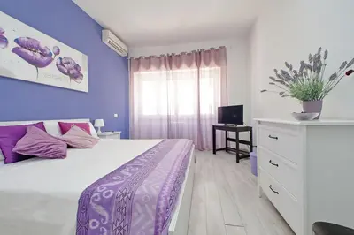 a bedroom with a large bed with purple walls at Victoria Apartment in Rome