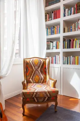 a chair sitting in front of a book shelf at Suite Elizabeth in Barberini in Rome