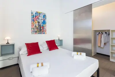 a white bed with red pillows in a room at Loft Ostiense Blue in Rome