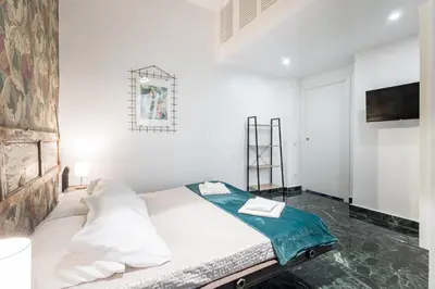 a white bedroom with a bed and a tv at DOMUS Generale Ezio in Rome
