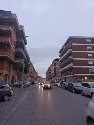 a yellow car driving down a city street with buildings at casaemily TrenoFiumicinoAir-VillaBonelli-Ostiense in Rome