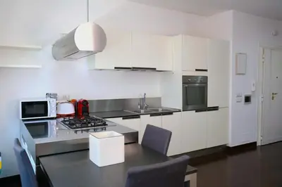 a kitchen with white cabinets and a table with chairs at Nice flat near Trastevere Station in Rome