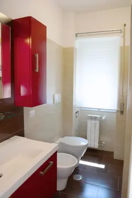 a bathroom with a white toilet and red cabinets at Nice flat near Trastevere Station in Rome